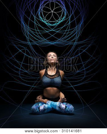 Beautiful Young Woman In Padmasana Pose. Colorful Mandala On Black Background Behind