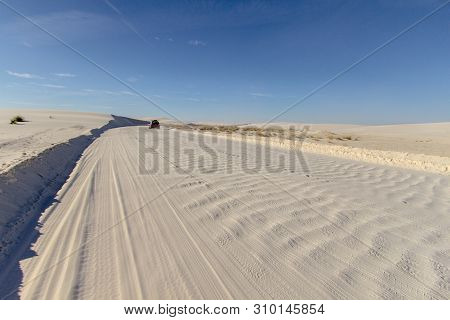 Car Driving Through Desert. Single Car Drives Down A Rough Washboard Dirt Road Through A Remote Dese