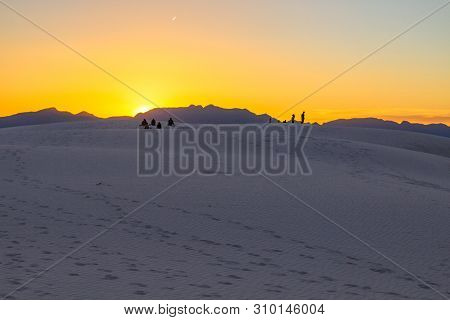 Tourists Watching A Desert Sunset. Tourists Stand On Top Of A Sand Dune Admiring The Sunset Horizon 