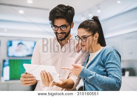 Young Hipster Modern Couple In The Mobile Store Testing Tablet.