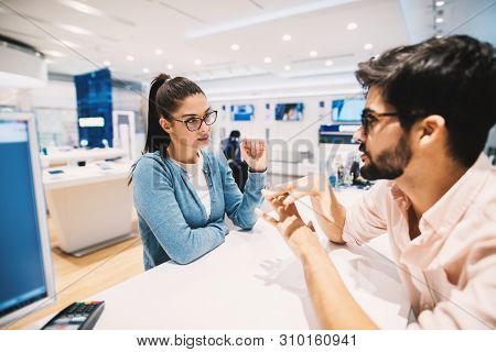 Beautiful Young Brunette Talking With Employe In The Tech Store.