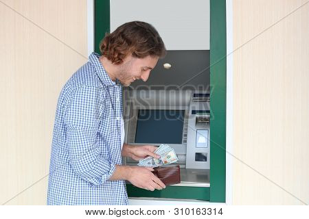 Young Man With Money Near Cash Machine Outdoors