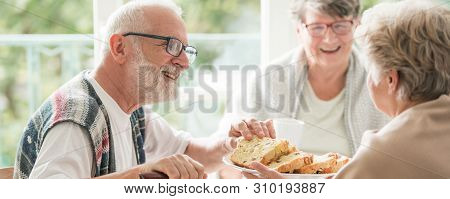Happy Seniors Sharing Cake During Coffee Meeting At Nursing Home