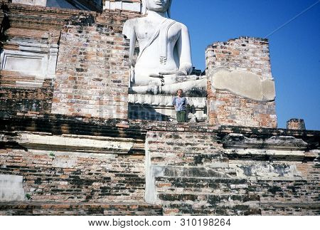 Ayutthaya / Thailand - Circa 2000: An American Tourist Poses In Front Of An Ancient Buddha Statue At