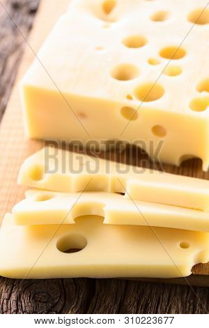Piece And Slices Of Emmental, Emmentaler Or Emmenthal Cheese On Wooden Cutting Board (selective Focu