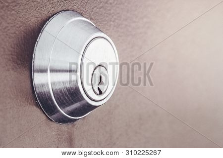 Modern New Metallic Grey Shiny Keyhole On Door Background. Side View Of Keyway With Sun Light And Co