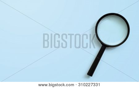 Magnifying Glass On Blue Colour Background With Copy Space. Searching Information Data Concept