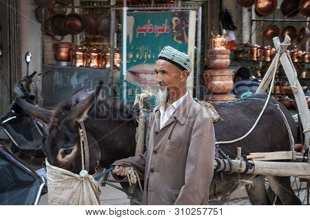 Kashgar, Xinjiang, China - August 14, 2012: Uyghur Man With A Donkey At A Street Market In The City 