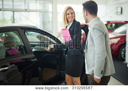Professional Salesperson During Work With Customer At Car Dealership.