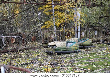 Old Broken Rusty Metal Radioactive Yellow Cars, Childrens Electric Cars, Abandoned Among Vegetation,