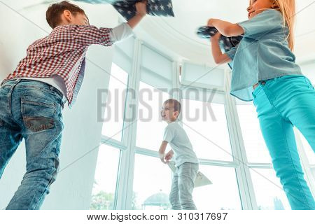 Low Angle Of Positive Happy Children Throwing Pillows