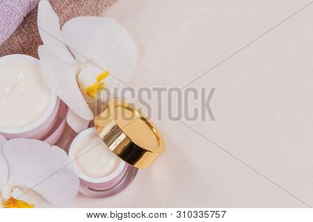 Bottles Of Hand Or Face Cream Or Facial Mask, Towels And White Orchid Flowers On Light Background. N