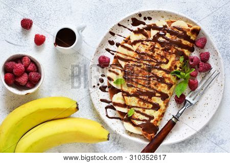 Crepe With Chocolate Paste, Banana And Raspberries On A Concrete Background. Tasty Breakfast.