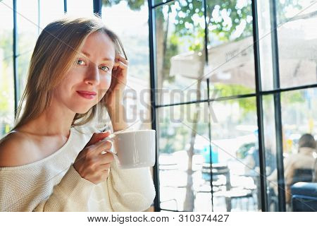 Alone Time Without Phone Concept. Young Beautiful Woman Wearing Off Shoulder Sweater Having Cup Of C