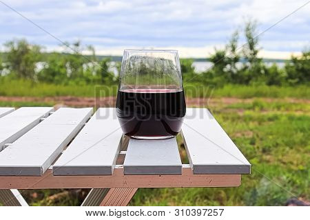 Closeup Of A Stemless Wineglass With A Lake In The Background