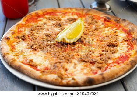 Close Up Picture Of A Delicious Pizza With Tuna Fish And Lemon On Top At A Terrace By The Seaside