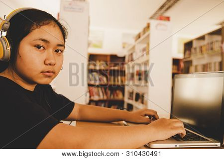 In The Library - Young Girl Student Using Her Laptop In A Library