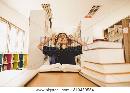 Shot Of Young Asian Female Student Sitting At Table. Young Female Student Studying In Library.