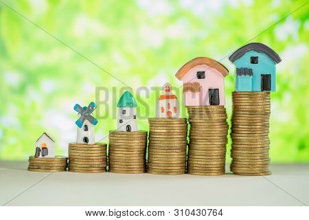 Mini House On Stack Of Coins With Green Blur Background.