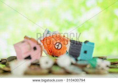 Mini House On Pile Of Coins With Green Blur Background.