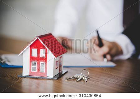 Estate Agent Giving House Keys To Female And Sign Agreement In Office