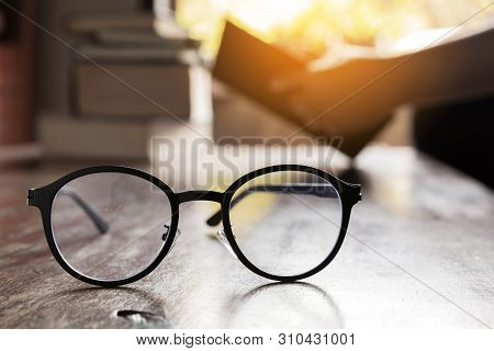 Focus At Glasses And Background Of Woman Sitting In A Cafe, Reading Book.