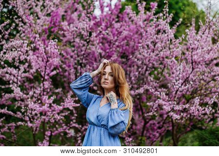 Beautiful Smilling Redhead Woman In Spring Time Blossom Cherrytrees Garden. Perfect Time For A Walk.