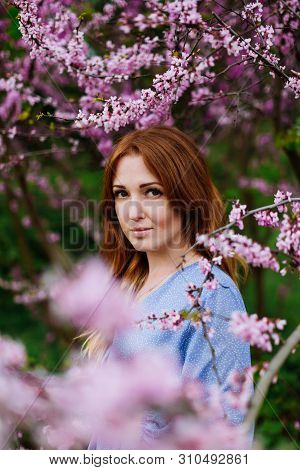 Beautiful Smilling Redhead Woman In Spring Time Blossom Cherrytrees Garden.
