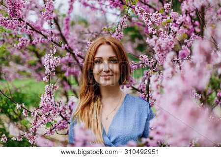 Beautiful Smilling Redhead Woman In Spring Time Blossom Cherrytrees Garden.