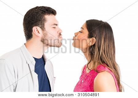 Young Boyfriend And Girlfriend Puckering Lips While Preparing For Kiss Over Isolated Background
