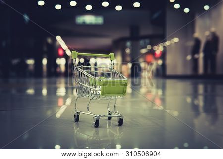 Conceptual Shot Of A Small Shopping Cart Put On The Floor At Blur Background Of Shopping Centre. Pet