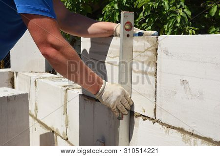 Builder Laying Aac, Autoclaved Aerated Concrete Blocks House Wall And Measure  With Spitit Level