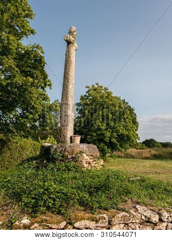 Old Monument Made Of Stone Standing On A Meadow In France