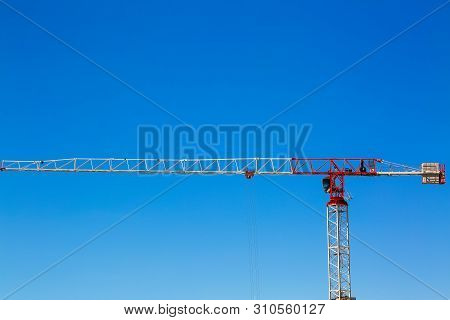 Industrial Construction Crane Or Column-jib Crane With Cabin Works  On The Construction Site And Blu