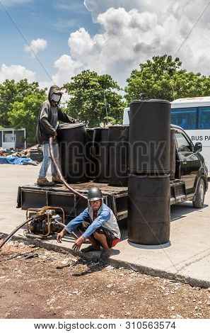 Makassar, Sulawesi, Indonesia - February 28, 2019: Paotere Old Port. Two Guys Pump Fuel From Black B