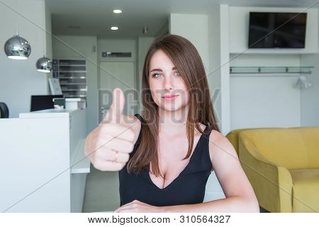 Close Up Portrait Of Happy Smiling Young Woman With Deep Decollete And Thumb Up Hand Sitting Behind 