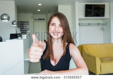 Close Up Portrait Of Happy Smiling Young Woman With Deep Decollete And Thumb Up Hand Sitting Behind 