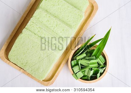 Sliced Pandan Bread On Wooden Plate And Sliced Pandan Leaf In A Bowl On White Background, Top View