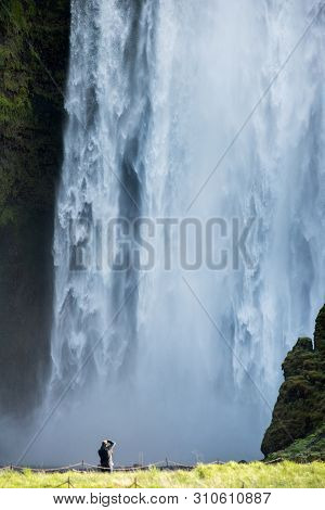 Tourist Photographing Skogafoss Waterfall, Iceland