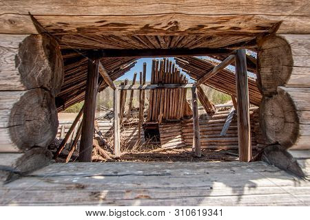 View Through A Window Into An Old Wooden Yurt. Frame From The Window. Log Wall, Parallel Bars. Insid