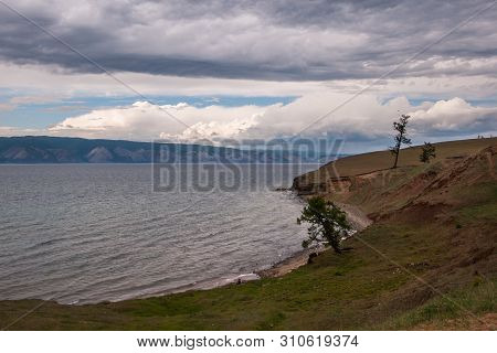Baikal Lakeside With Mountains In The Background And Beautiful Clouds. Trees On The Lake Shore. Lake