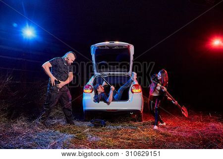Couple Of Thugs Near Car Trying To Kill Young Guy In The Trunk At Night. Photoshoot About Life Of Gu