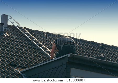 Roofer Works On An Unfinished Roof. Installs Roof Shingles