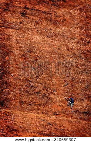 Rock climber tourist on holiday vacation climbing standstone cliff for the first time