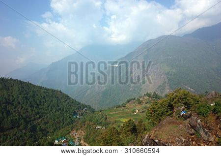 Small propeller airplane flying from TenzingâHillary Airport in Lukla on background of green Himalaya Mountains, Nepal