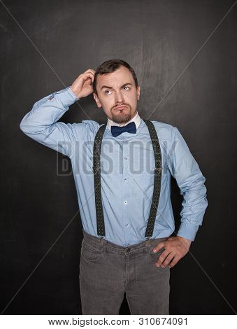 Handsome Business Man Scratching His Head On Blackboard