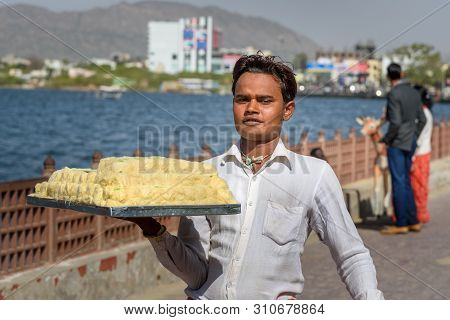 Ajmer, India - February 07, 2019: Indian Guy Carries Sweets On Tray For Sale On The Street In Ajmer