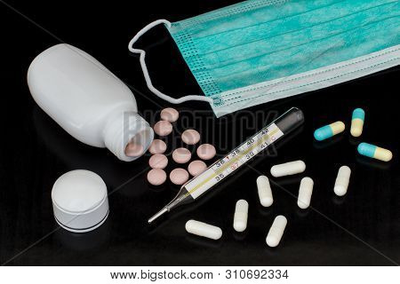 Procedure Earloop Face Mask, Mercury Thermometer, Different Pills With Bottle On Dark Background. To