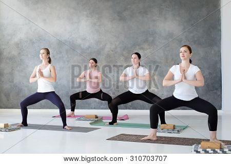 Group Of Concentrated Yoga Students Doing Rudrasana Or Goddess Pose