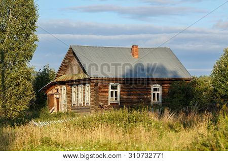 Russian Village In Summer. Old Log House With A Courtyard Overgrown With Grass On A Sunny Summer Day